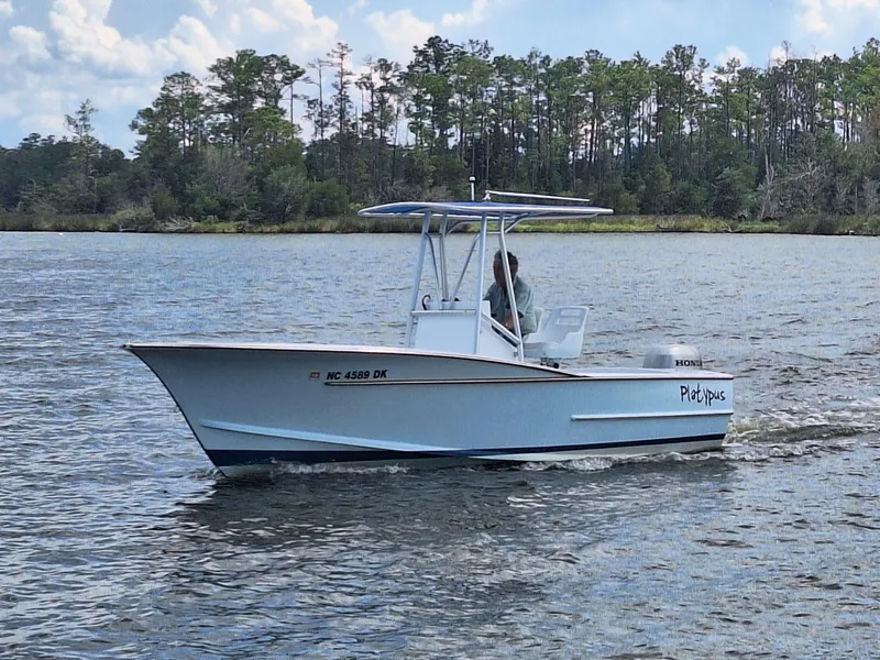 Slide: The Image of 2008 Custom Carolina boat cruising on a lake with trees in the background. - 2