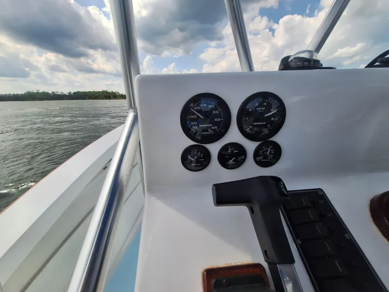 Slide: The Image of Custom Carolina 2008 boat dashboard with gauges and throttle, cruising on a lake under cloudy sky. - 23
