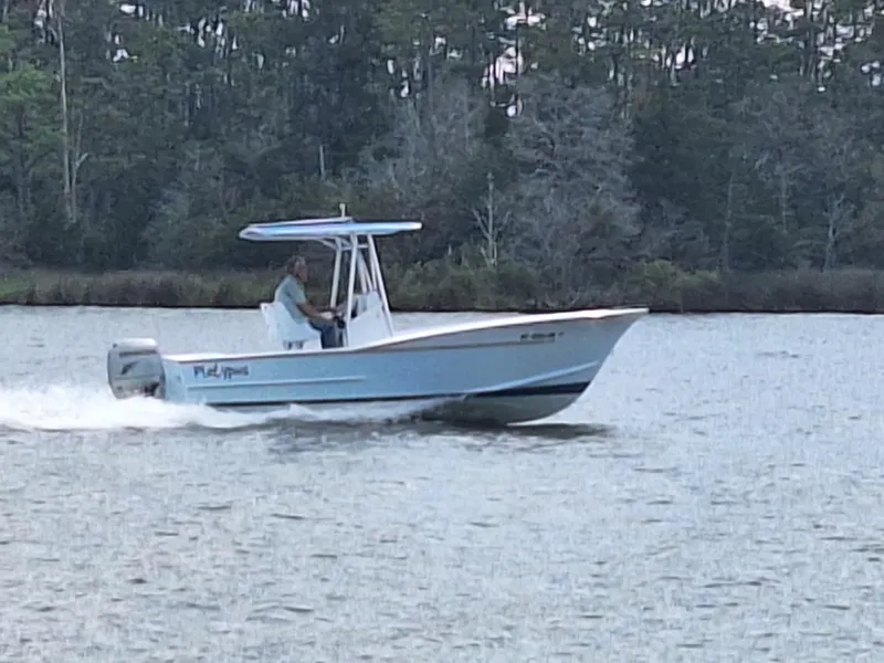 Slide: The Image of 2008 Custom Carolina boat cruising on a lake with a forested background. - 8
