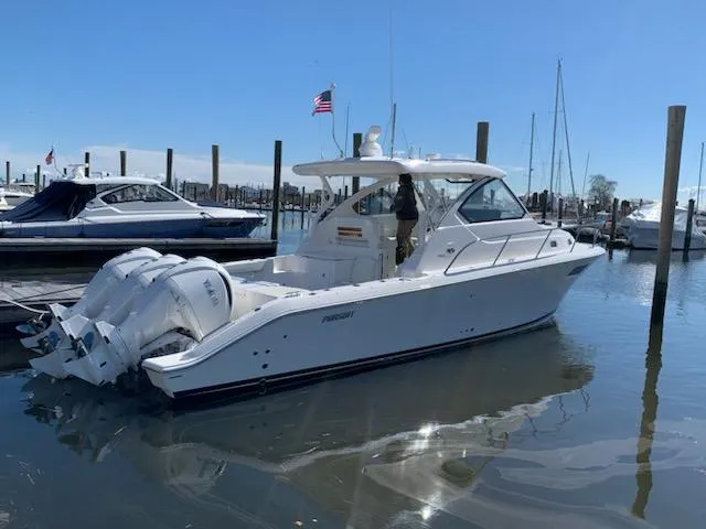 Slide: The Image of 2022 Pursuit OS 355 boat docked in a marina with twin outboard engines. - 0