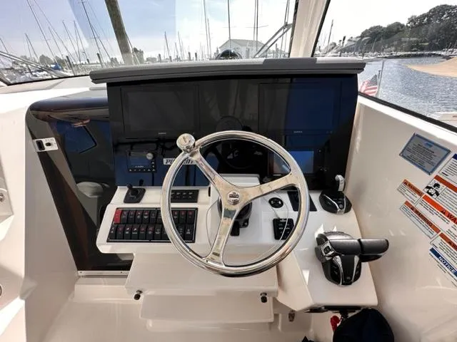 Slide: The Image of 2022 Pursuit OS 355 boat helm with steering wheel and control panel. - 10