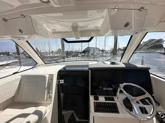 Slide: The Image of 2022 Pursuit OS 355 boat helm with modern controls and marina view. - 14