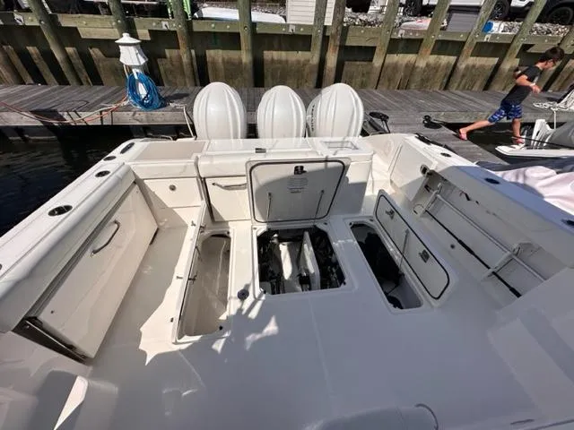 Slide: The Image of 2022 Pursuit OS 355 boat with open hatches and triple outboard engines at dock. - 15