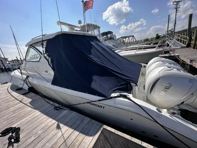Slide: The Image of 2022 Pursuit OS 355 boat docked with Yamaha engines, covered with a blue tarp. - 17