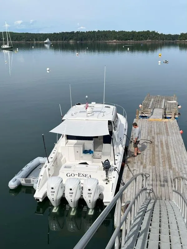Slide: The Image of 2022 Pursuit OS 355 boat docked at a serene lake with a wooden pier. - 2