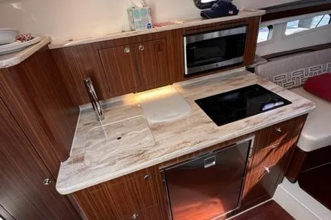 Slide: The Image of Modern kitchen area in 2022 Pursuit OS 355 boat with stove, sink, and microwave. - 35