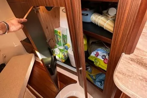 Slide: The Image of Storage cabinet in 2022 Pursuit OS 355 boat with cleaning supplies and paper towels. - 38