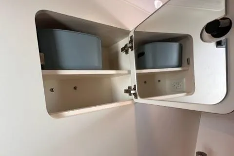 Slide: The Image of Open cabinet with shelves inside a 2022 Pursuit OS 355 boat. - 49