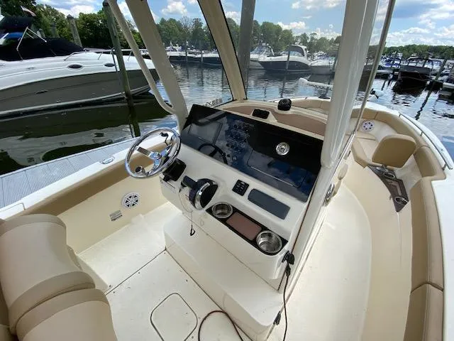 Slide: The Image of 2020 Scout 235 XSF boat interior with steering console and docked boats in background. - 15