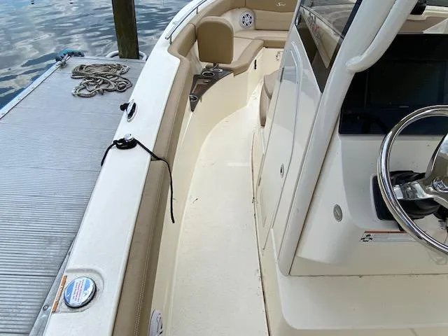 Slide: The Image of 2020 Scout 235 XSF boat docked, showing interior seating and steering console. - 18