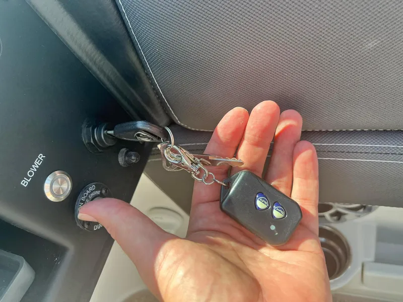 Slide: The Image of Hand holding keys in a 2024 Crownline 260SS boat ignition. - 15