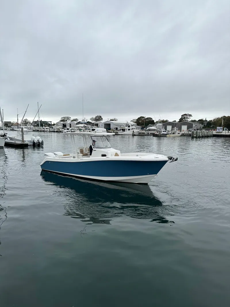 Slide: The Image of 2022 Edgewater 280 CC boat docked in a marina on a cloudy day. - 1