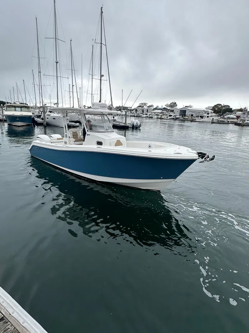 Slide: The Image of 2022 Edgewater 280 CC boat docked in a marina on a cloudy day. - 2