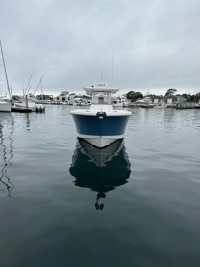 Slide: The Image of 2022 Edgewater 280 CC boat docked in a marina on a cloudy day. - 3