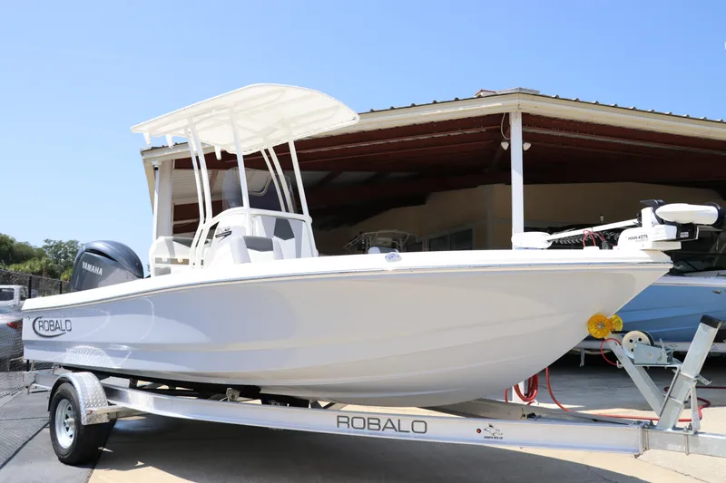 Slide: The Image of 2024 Robalo 206 Cayman boat on trailer, parked outdoors under clear blue sky. - 2
