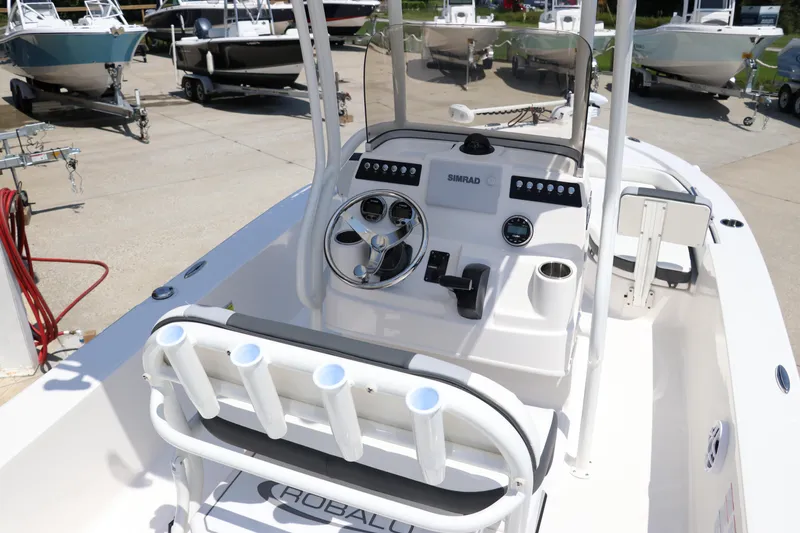 Slide: The Image of 2024 Robalo 206 Cayman boat console with steering wheel and rod holders, docked outdoors. - 6