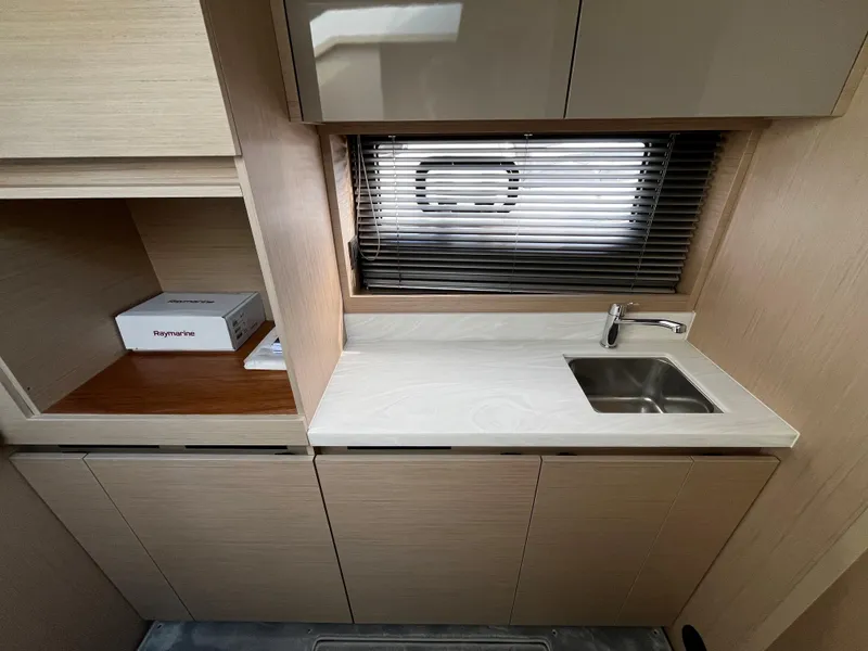 Slide: The Image of 2024 Jeanneau DB/43 OB boat interior kitchen with sink and storage cabinets. - 21