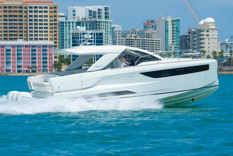 Slide: The Image of 2024 Jeanneau DB/43 OB cruising on water with city skyline in background. - 23