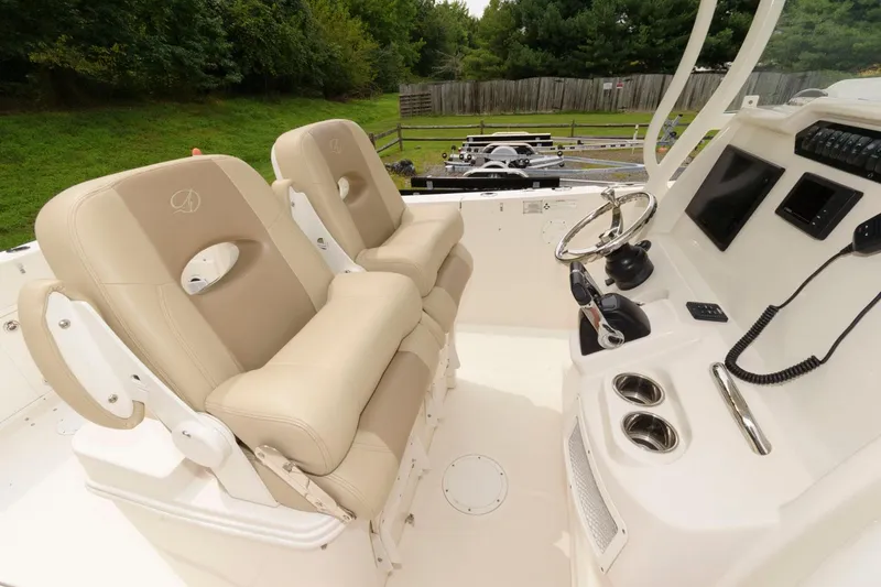 Slide: The Image of 2018 Sailfish 290 CC boat cockpit with dual beige captain's chairs and control panel. - 15