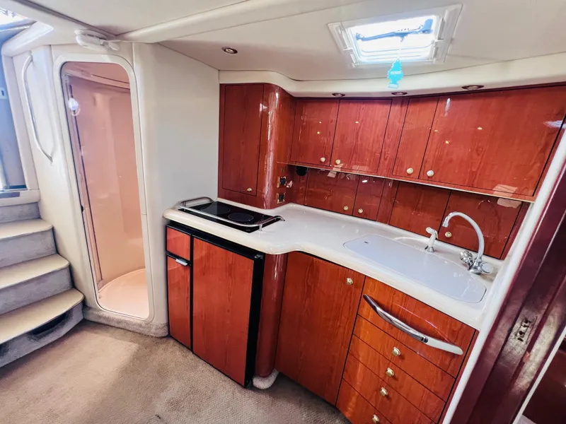 Slide: The Image of Interior of a 1998 Sea Ray Express Cruiser with wooden cabinetry and compact kitchen area. - 24
