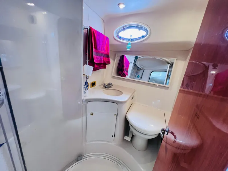 Slide: The Image of 1998 Sea Ray Express Cruiser bathroom with sink, toilet, mirror, and porthole window. - 25
