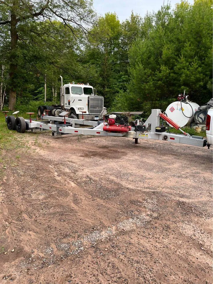 Slide: The Image of A large truck and trailer parked on a dirt road surrounded by trees. - 31