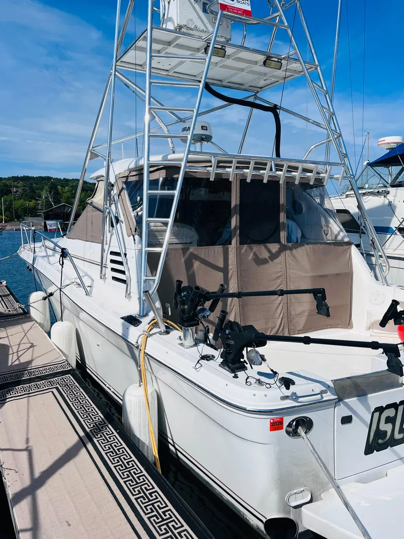 Slide: The Image of 1998 Sea Ray Express Cruiser docked, featuring a tall tower and fishing equipment. - 6