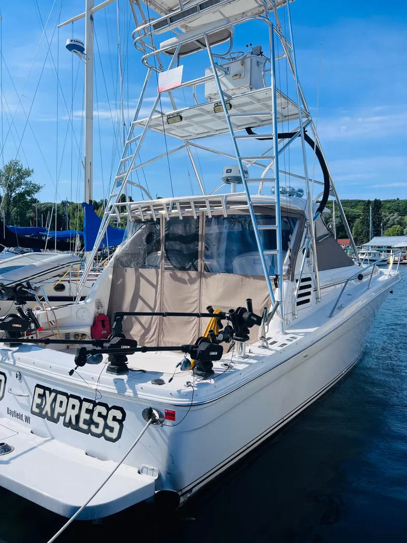 Slide: The Image of 1998 Sea Ray Express Cruiser docked at marina, featuring fishing equipment and tower. - 7