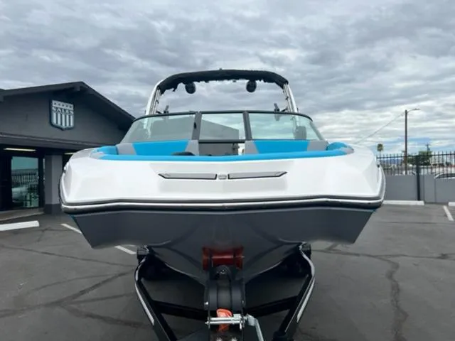 Slide: The Image of 2023 MasterCraft NXT22 boat with blue accents, parked outdoors under cloudy skies. - 3