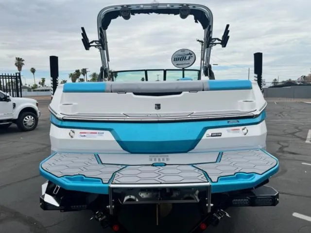 Slide: The Image of 2023 MasterCraft NXT22 boat, rear view, blue and white design, parked outdoors. - 7