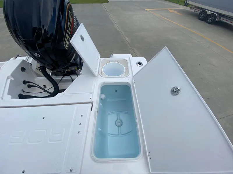 Slide: The Image of 2024 Robalo 246 Cayman boat with open storage compartments and outboard motor. - 11