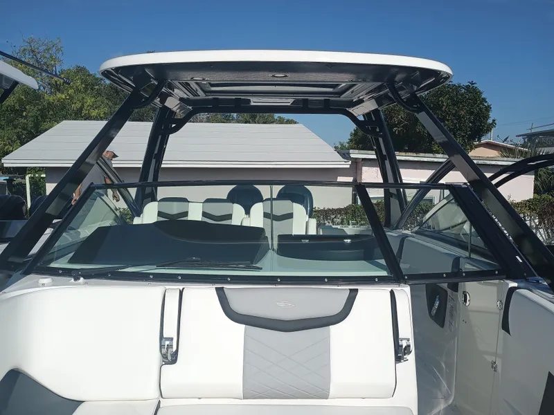 Slide: The Image of 2024 Chaparral 280 OSX boat with sleek design and spacious seating under a clear blue sky. - 7