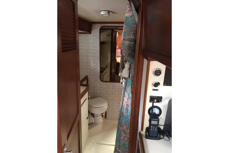 Slide: The Image of Interior of 1983 Stuart Marine 62 Custom Ketch, featuring a compact bathroom and floral curtain. - 16