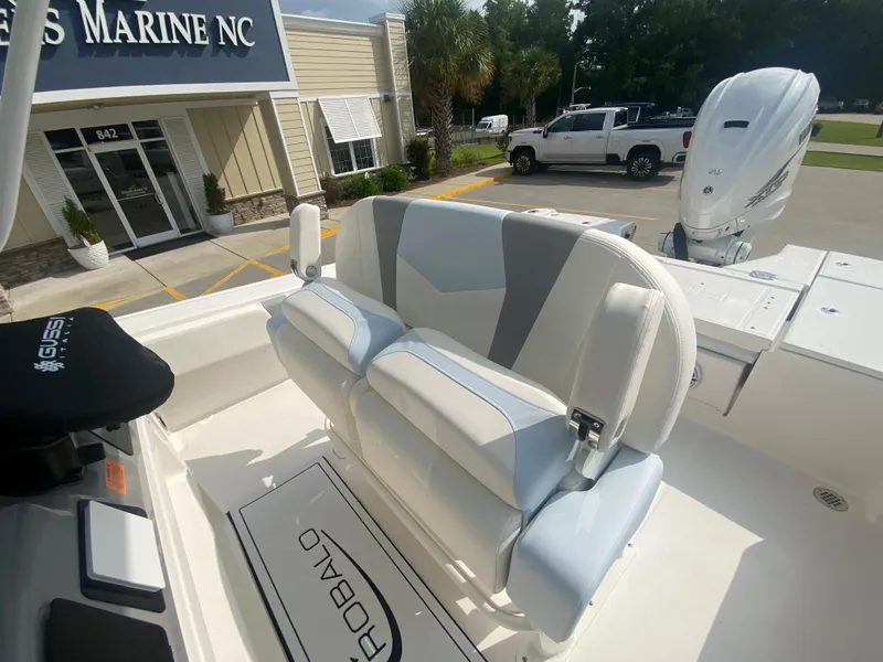 Slide: The Image of 2024 Robalo 266 Cayman boat with cushioned seating and outboard motor at a marine dealership. - 12