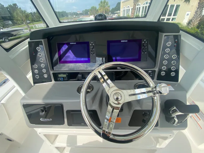 Slide: The Image of 2024 Robalo 266 Cayman boat dashboard with dual Simrad displays and steering wheel. - 13