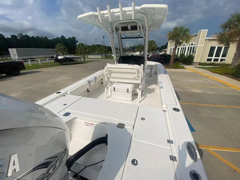 Slide: The Image of 2024 Robalo 266 Cayman boat, white exterior, docked at a marina under a cloudy sky. - 6