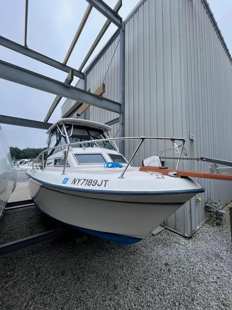 Slide: The Image of 1987 Grady-White 24 Offshore boat stored outdoors near a metal building. - 10