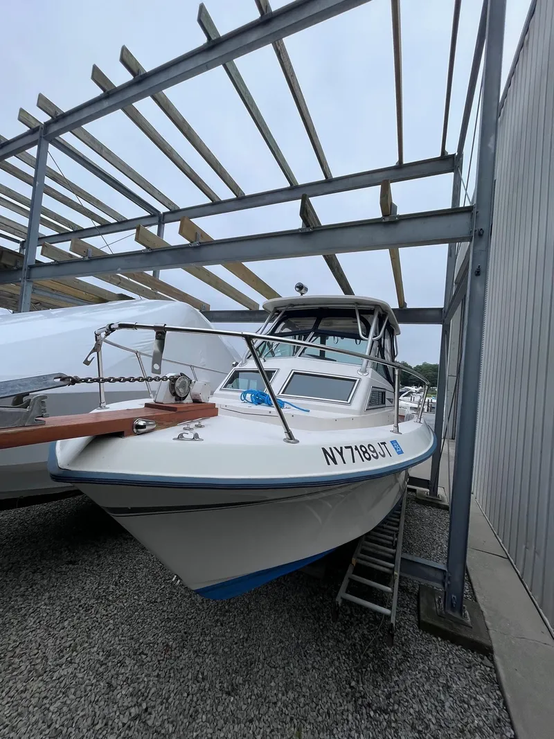 Slide: The Image of 1987 Grady-White 24 Offshore boat in storage, under metal framework, with visible registration number. - 11
