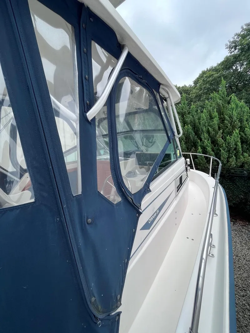 Slide: The Image of 1987 Grady-White 24 Offshore boat with blue canopy and railing, docked near greenery. - 2