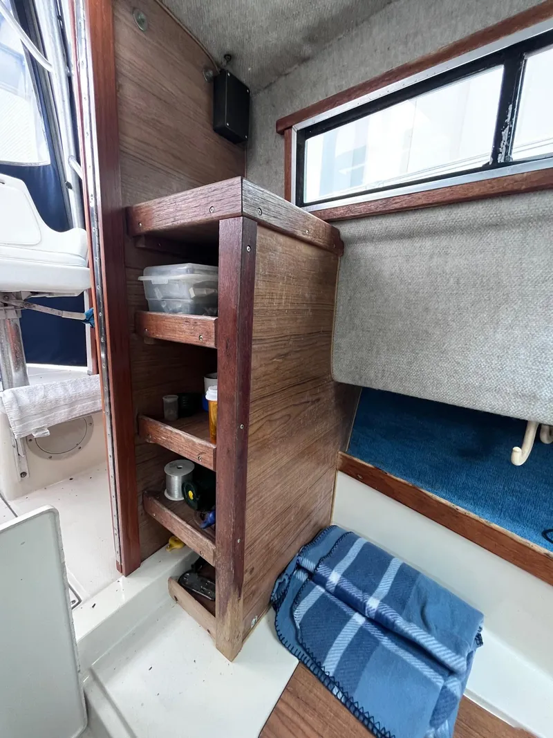 Slide: The Image of Interior of 1987 Grady-White 24 Offshore boat with wooden shelving and blue blanket. - 7