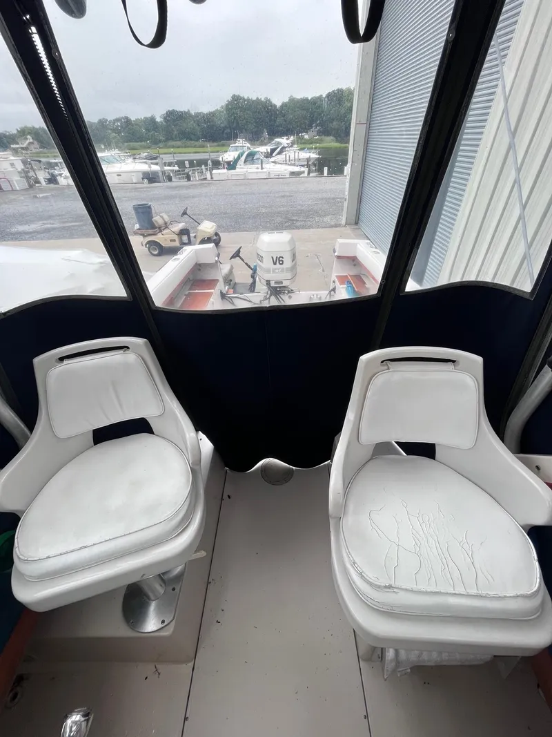 Slide: The Image of 1987 Grady-White 24 Offshore boat interior with two white seats and marina view. - 9