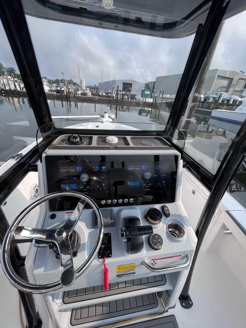 Slide: The Image of 2023 Crevalle 24 HCO boat dashboard with steering wheel and controls, docked at marina. - 1