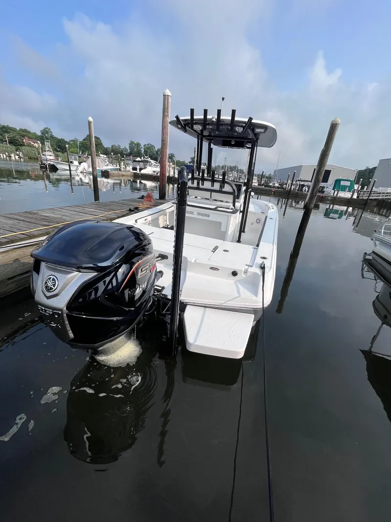 Slide: The Image of 2023 Crevalle 24 HCO boat docked in a marina, featuring a powerful outboard motor. - 10