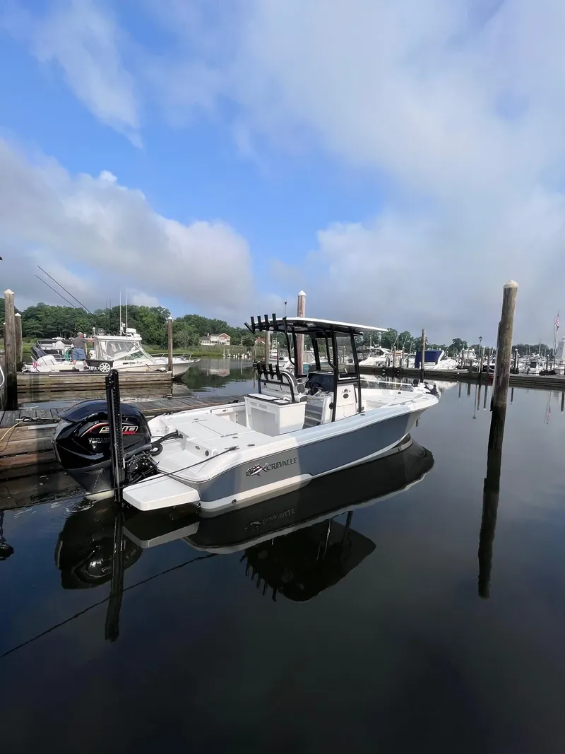 Slide: The Image of 2023 Crevalle 24 HCO boat docked in a marina under a partly cloudy sky. - 13