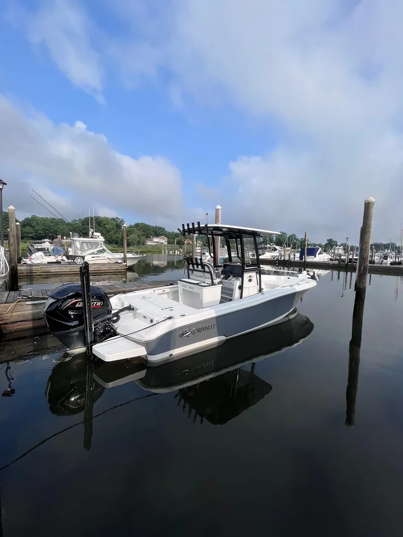 Slide: The Image of 2023 Crevalle 24 HCO boat docked in a marina under a clear blue sky. - 4
