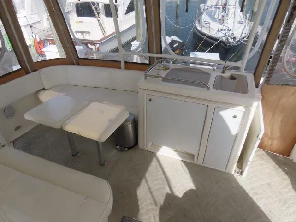 Slide: The Image of 2004 Cruisers Yachts 405 Express Motoryacht interior with seating and kitchenette, docked at marina. - 11