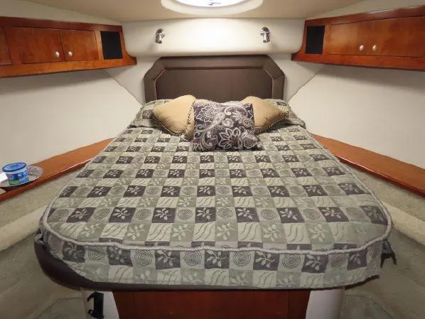 Slide: The Image of Luxurious 2004 Cruisers Yachts 405 Express Motoryacht bedroom with patterned bedding and wooden cabinets. - 14