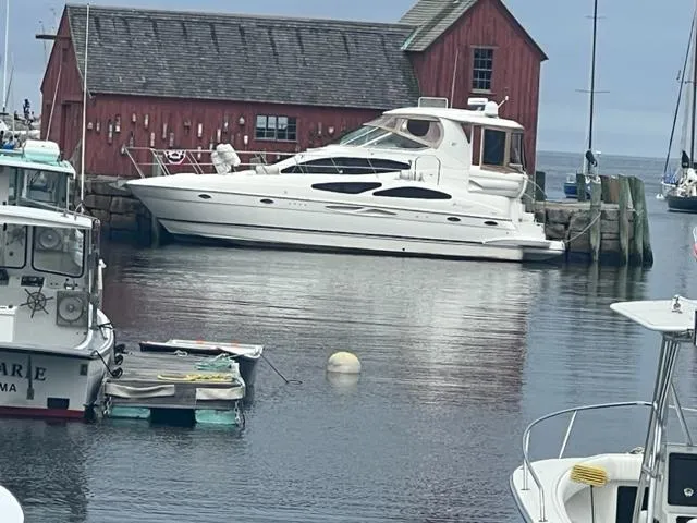 Slide: The Image of 2004 Cruisers Yachts 405 Express Motoryacht docked near a rustic red boathouse. - 3