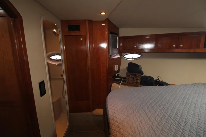 Slide: The Image of 2004 Cruisers Yachts 405 Express Motoryacht cabin with bed, wooden cabinets, and porthole window. - 38