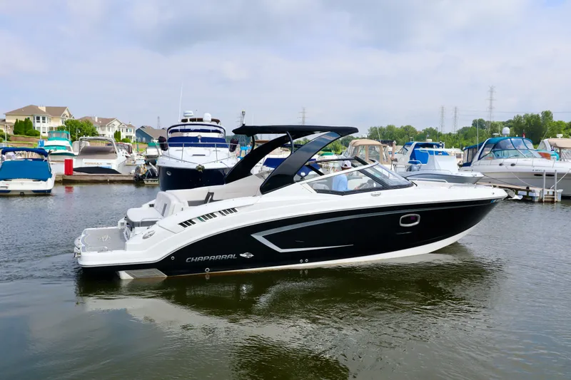 Slide: The Image of 2016 Chaparral 307 SSX boat docked in a marina, surrounded by other vessels. - 14